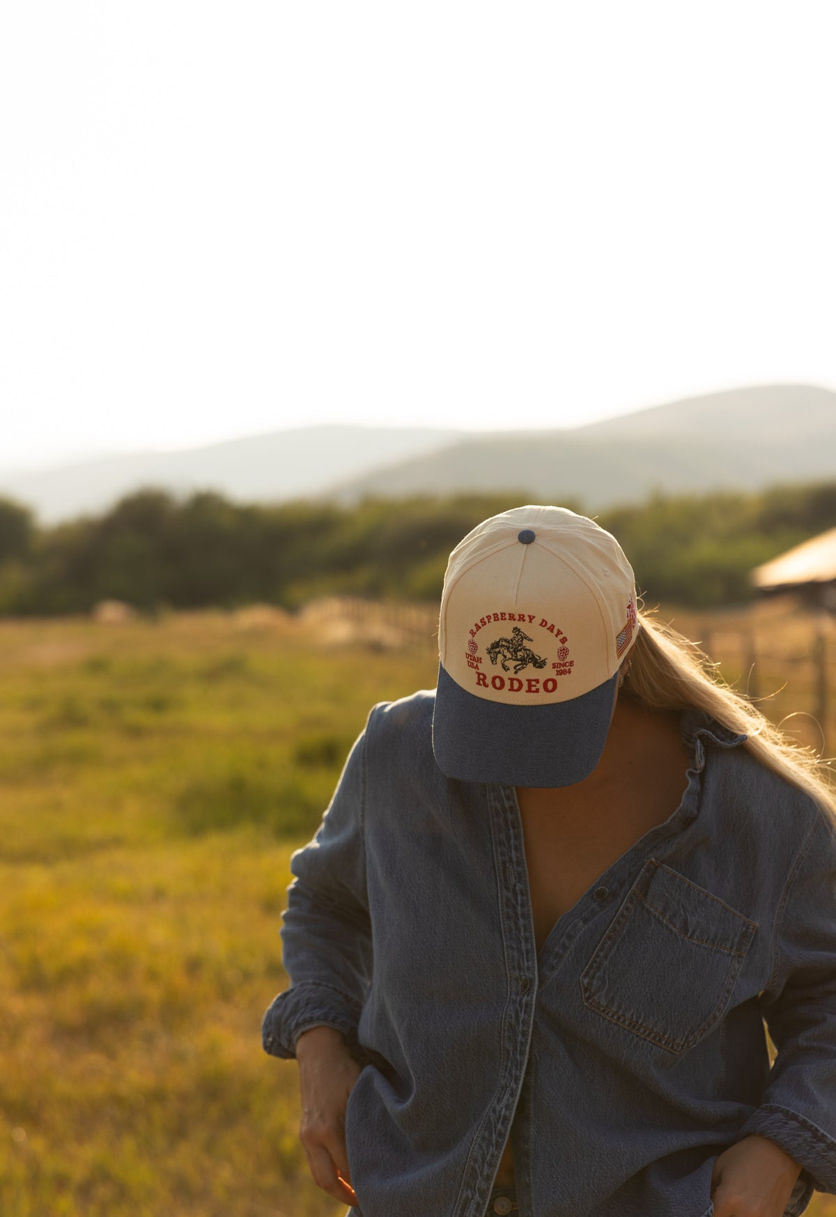 Woman in a Bull River cap in a field at golden hour
