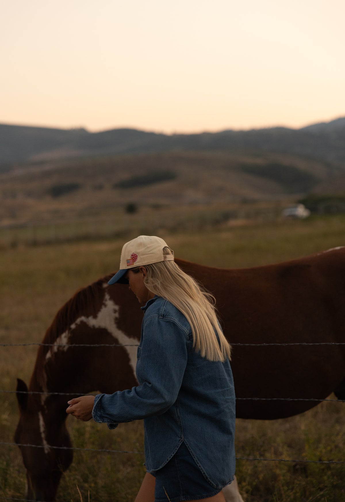 Woman with a horse wearing a Bull River Raspberry Days cap