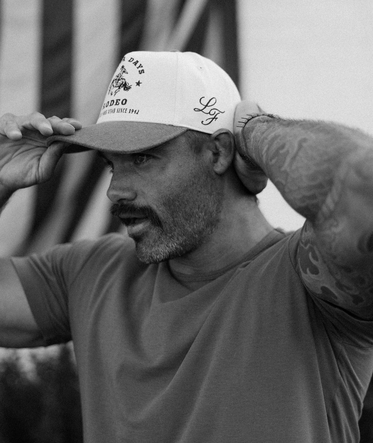 Black and white close-up of a man adjusting a custom Bull River cap