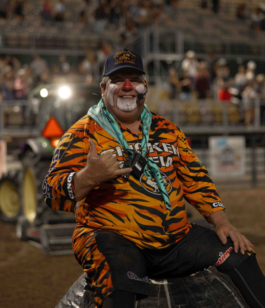 Rodeo clown in a custom tiger-stripe Bull River shirt and Utah's Own PRCA Rodeo hat giving a shaka sign