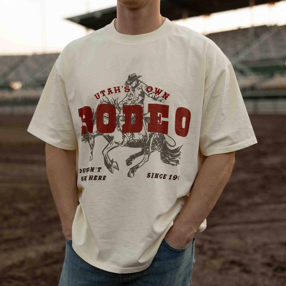 Person wearing a t-shirt with a rodeo graphic and text in an outdoor setting